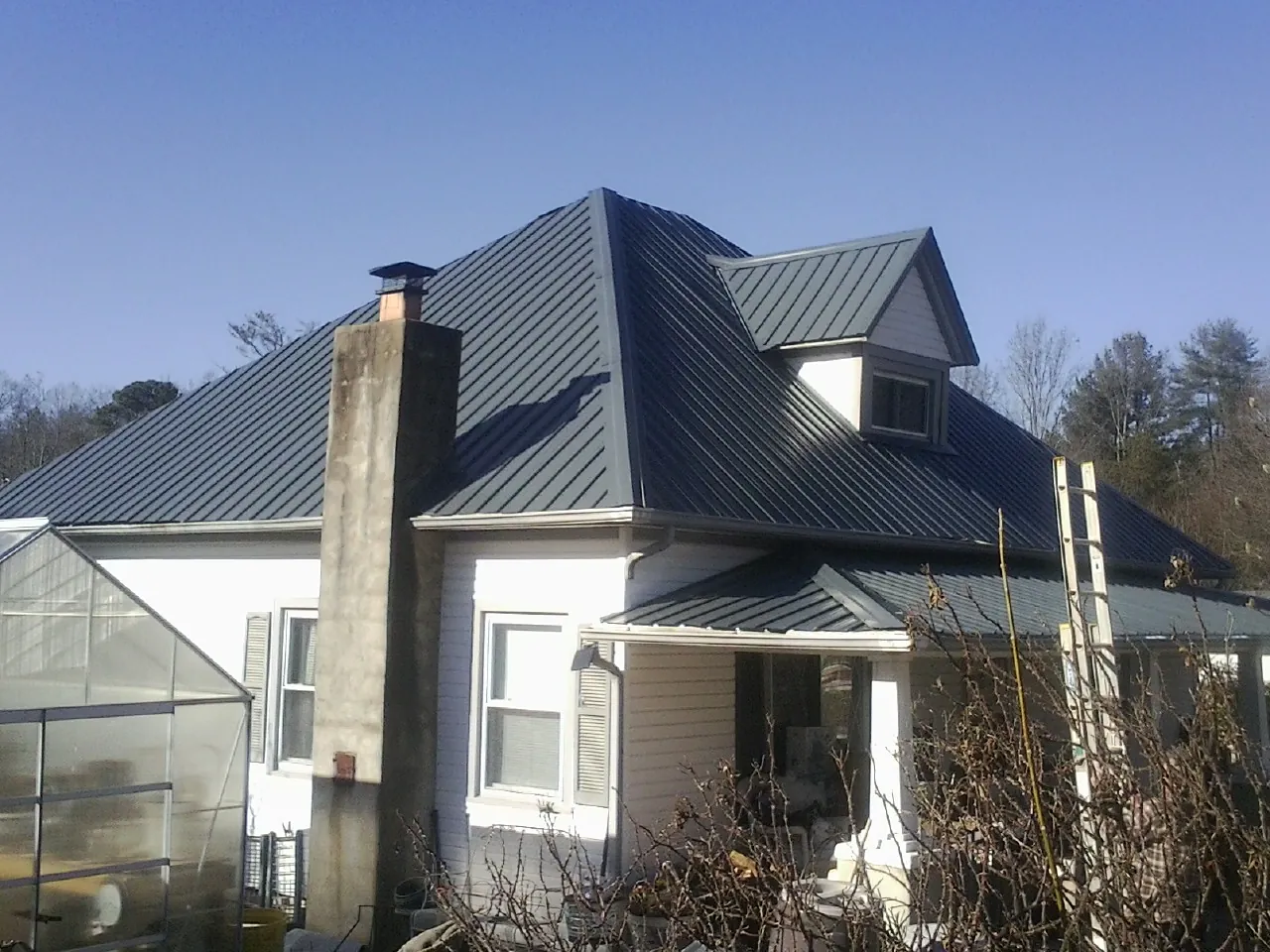 Dark blue standing seam metal roof on a white farmhouse with dormer — Slate & Tile Roof Repair by Roofing Brothers in Lemont Furnace