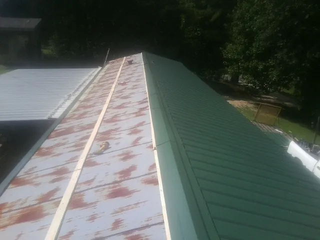 Old rusted panels beside newly installed green metal roofing — Wind Damage Roof Repair by Roofing Brothers in Lemont Furnace