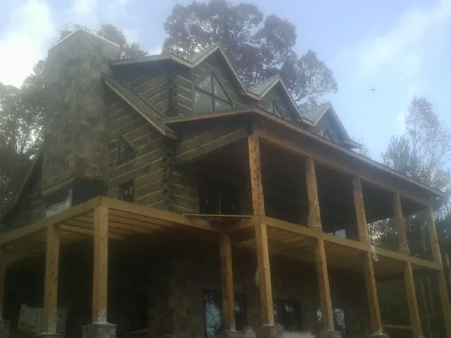 Stone chimney and dormers on a large log home with a timber porch in Lemont Furnace