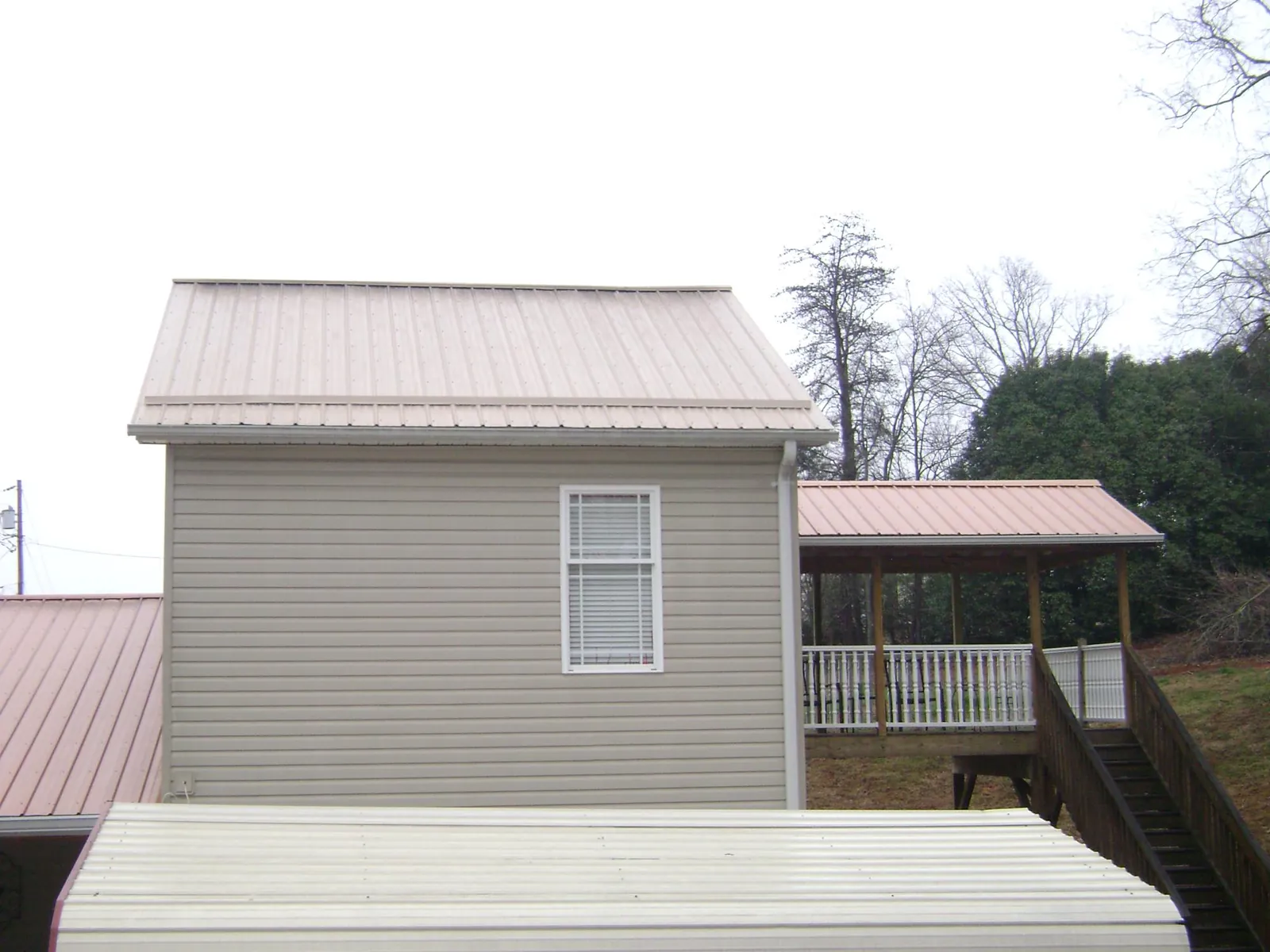 Tan metal roofs on a two story addition and attached porch, from a Roof Replacement job in Lemont Furnace