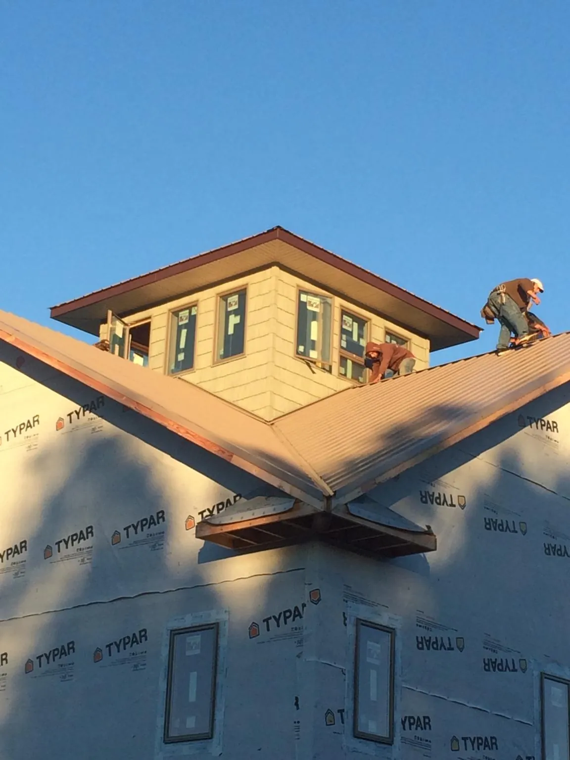 Roofers working around a rooftop cupola on a new metal roof at sunset — Roof Waterproofing in Lemont Furnace by Roofing Brothers